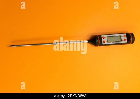 Thermomètre électronique à viande sur fond orange . Banque D'Images
