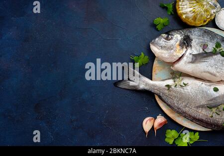 Deux poissons dorado avec des tranches de citron sur fond en bois bleu foncé Banque D'Images