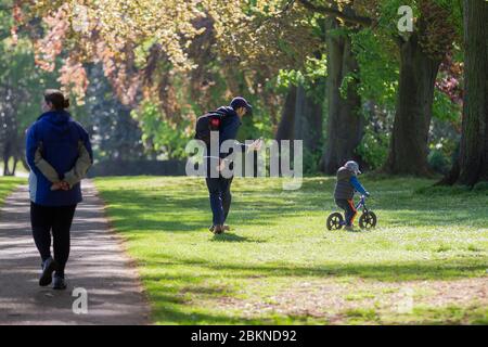 Northampton, Royaume-Uni. 5 mai 2020. Une matinée ensoleillée et lumineuse à Abington Park et une jeune famille emparent leur fils pour une promenade à vélo sur l'avenue des arbres pendant l'exercice du matin alors que le confinement continue à cause de Covid-19. Crédit : Keith J Smith/Alay Live News Banque D'Images