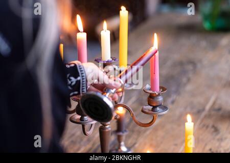 Une femme illuminant différentes bougies de couleur dans un porte-bougie en métal vintage pour créer une atmosphère agréable dans son loft. Un style éclectique de vie avec un Banque D'Images