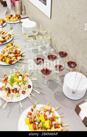 Table de réception avec assiettes blanches avec brochettes de légumes et verres avec vin blanc et rouge Banque D'Images