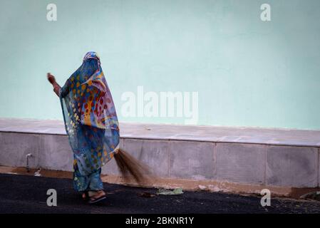 Femme indienne élégante qui balaie. Fond bleu pâle. Mandowa, Rajasthan, Inde Banque D'Images