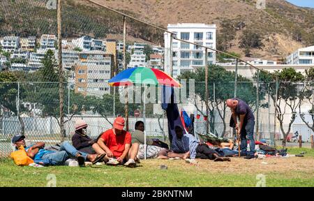 L'Afrique du Sud entre dans un confinement national du coronavirus, le 26 avril 2020. Les sans-abri se rassemblent devant un court de tennis à Sea point Cape Town. Banque D'Images