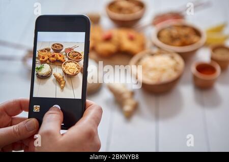 Femme prenant une photo avec un smartphone de poulet croustillant frite dans de la chapelure Banque D'Images