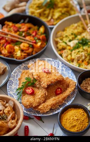 Cuisine asiatique servie. Assiettes, casseroles et bols pleins de nouilles sautés de poulet et légumes Banque D'Images