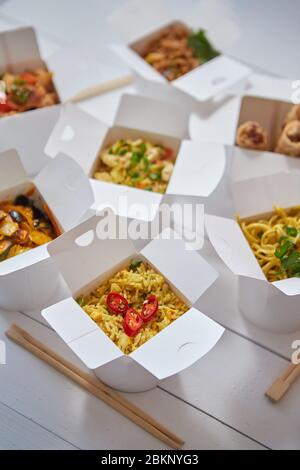 Concept asiatique de plats à emporter ou à livrer. Boîtes en papier placées sur une table en bois blanc Banque D'Images