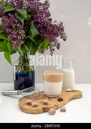 La boisson de café coréenne Dalgona fait de lait d'amande avec fleur de lilas sur fond blanc Banque D'Images