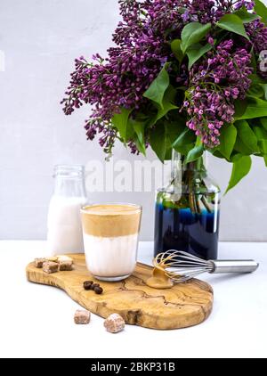 La boisson de café coréenne Dalgona fait de lait d'amande avec fleur de lilas sur fond blanc Banque D'Images