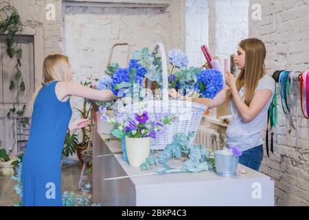 Deux artistes fleuristes professionnels, fleuristes en train de réaliser un grand panier floral avec des fleurs à l'atelier, fleuriste. Fleuriste, fait main, mariage Banque D'Images