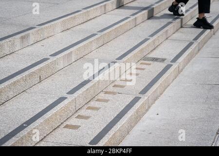 Une personne passe les marqueurs de mesure impériaux intégrés aux marches menant à la National Portrait Gallery de Trafalgar Square à Londres alors que le Royaume-Uni continue de se verrouiller pour aider à freiner la propagation du coronavirus. Banque D'Images