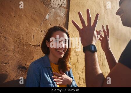 Un couple parlant et souriant, l'homme avec les mains levées. Banque D'Images