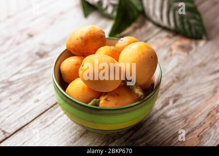 Mûr, Eriobotrya japonica, et feuilles de medlar vertes sur table en bois Banque D'Images