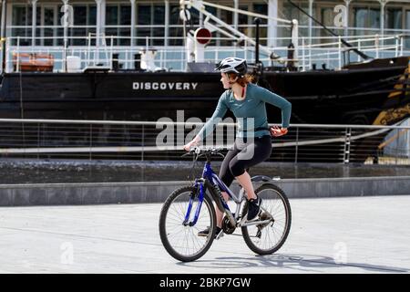 Dundee, Tayside, Écosse, Royaume-Uni. 5 mai 2020. Météo au Royaume-Uni : matin chaud et ensoleillé à Dundee avec des températures atteignant 14°C. Une cycliste féminine qui profite du soleil chaud tout en effectuant des exercices en plein air en passant devant le bateau RRS Discovery le long du front de mer pendant les restrictions de confinement de Covid-19 dans toute l'Écosse. Crédit : Dundee Photographics/Alamy Live News Banque D'Images