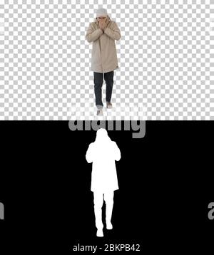 Homme en tenue d'hiver marchant et toussant, Alpha Channel Banque D'Images