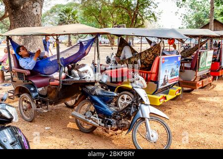 Remork chauffeurs de taxi se détendre comme leurs clients visitent le complexe du Temple d'Angkor Wat, Siem Reap, province de Siem Reap, Cambodge. Banque D'Images