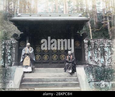 [ 1890 Japon - prêtres bouddhistes au temple japonais de Nikko ] — deux prêtres bouddhistes devant une porte de bronze à Nikko, préfecture de Tochigi. photographie d'albumine vintage du xixe siècle. Banque D'Images