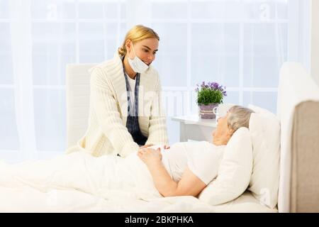 la santé à l'hôpital. fille ou parent de femme visitant la femme senior couché au lit pendant qu'elle reçoit un traitement dans la salle de clinique médicale Banque D'Images