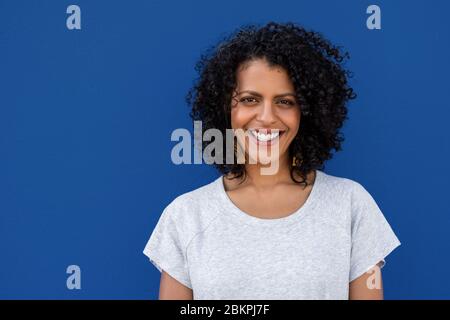 Jeune femme souriante debout sur fond bleu coloré Banque D'Images