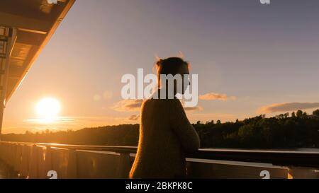 Femme debout sur le pont du bateau de croisière et regardant le paysage. Coucher de soleil, heure d'or. Concept de nature et de voyage Banque D'Images