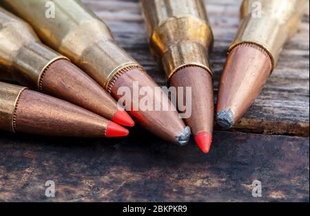 Un gros plan de cinq balles de fusil de calibre différent ensemble sur un fond en bois, trois ont des bouts rouges Banque D'Images