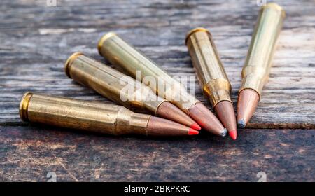 Cinq balles de fusil de calibre différent ensemble sur un fond en bois, trois ont des bouts rouges Banque D'Images