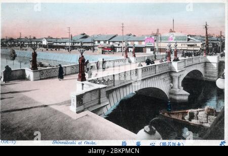 [ 1910s Japon - Pont Shinsaibashi, Osaka ] — Pont Shinsaibashi traversant le canal Nagahori à Osaka, Japon. Le pont de pierre de cette image a été ouvert en 1909 (Meiji 42) et a remplacé un pont d'acier de fabrication allemande en usage depuis 1873 (Meiji 6). Le photographe regarda vers le nord. carte postale vintage du xxe siècle. Banque D'Images