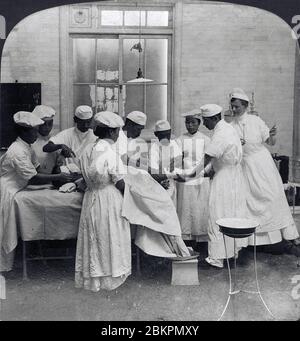 [ 1900 Japon - chirurgie pendant la guerre russo-japonaise ] — UNE équipe médicale japonaise ampute la jambe brisée d'un soldat blessé dans une salle d'opération de l'hôpital de la Réserve militaire d'Hiroshima pendant la guerre russo-japonaise (1904-1905). Une infirmière de la Croix-Rouge américaine aide. Vers 1904 (Meiji 37). Bien que ce ne soit pas le cas, la Dre Anita McGee, qui a fondé le US Army Nurse corps, a observé cette opération. chaîne stéréo du xxe siècle. Banque D'Images