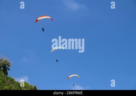 Parapente dans le ciel. Trois parapentes uniques volent en été sur l'île tropicale de Bali. Magnifique parapente en vol sur un backgrou de turquise Banque D'Images