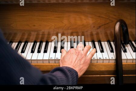 Main d'un homme âgé au piano et bâton de marche ayant une leçon de piano. Concept: Activité de vieillesse, stimulation, apprentissage, jamais trop vieux, maintien jeune. Banque D'Images