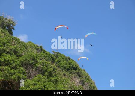 Parapente dans le ciel. Trois parapentes uniques volent en été sur l'île tropicale de Bali. Magnifique parapente en vol sur un backgrou de turquise Banque D'Images