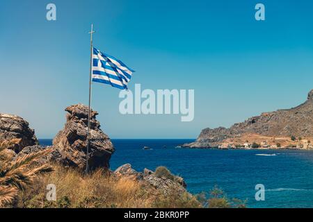 Drapeau grec dans le vent dans une baie rocheuse Banque D'Images