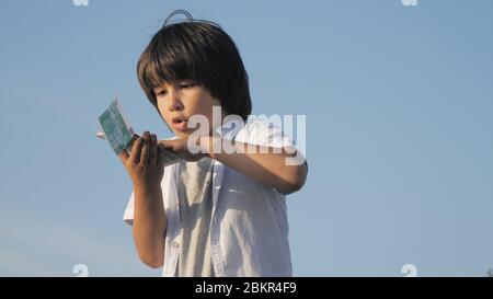 Un adorable garçon qui jette de l'argent sur des billets en euros. Banque D'Images