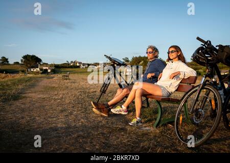 France, Finistère, Plougasnou, touristes cyclistes devant la plage de Saint-Samson au coucher du soleil, le long de la route maritime des vélos Banque D'Images