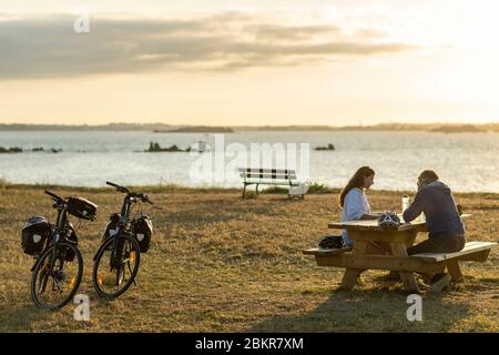 France, Finistère, Plougasnou, touristes cyclistes devant la plage de Saint-Samson au coucher du soleil, le long de la route maritime des vélos Banque D'Images