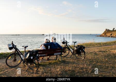 France, Finistère, Plougasnou, touristes cyclistes devant la plage de Saint-Samson au coucher du soleil, le long de la route maritime des vélos Banque D'Images