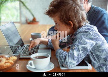 Utilisation des périphériques. Grand-père et son petit-fils passent du temps ensemble isolés à la maison. S'amuser, regarder en ligne, lire et nettoyer. Concept de quarantaine, famille, amour, royaltions, togetherness. Banque D'Images