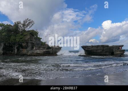 Des vagues se brisent sur une falaise au sommet de laquelle se trouve le temple hindou de Tanah Lot. Temple construit sur un rocher dans la mer au large de la côte de l'île de Bali, Indones Banque D'Images