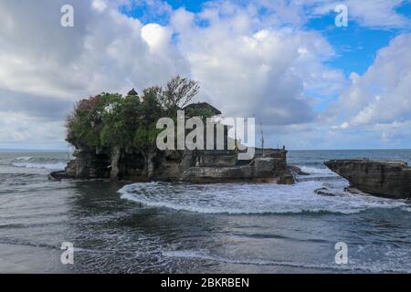 Des vagues se brisent sur une falaise au sommet de laquelle se trouve le temple hindou de Tanah Lot. Temple construit sur un rocher dans la mer au large de la côte de l'île de Bali, Indones Banque D'Images