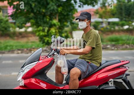 Un homme sur une moto portant un masque facial. Banque D'Images