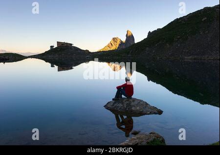 France, Savoie, Beaufortain, le refuge de Presset, randonneur contemplant le lever du soleil sur le refuge de Presset avec la Pierra Menta (2714m) et le Roc de la Charbonni?re (2738m) en arrière-plan Banque D'Images