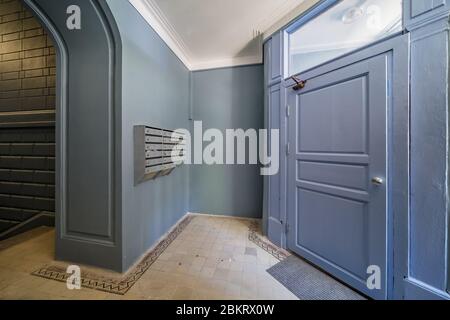 Couloir de porte dans l'entrée de l'ancien immeuble d'appartements avec boîtes aux lettres et murs gris récemment peints Banque D'Images