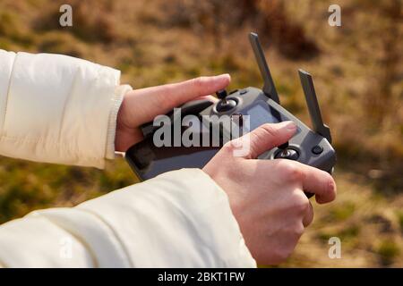 Gros plan des mains des femmes tenant une télécommande avec un smartphone. Concept de la vidéo aérienne, San Francisco, mai 2020 Banque D'Images