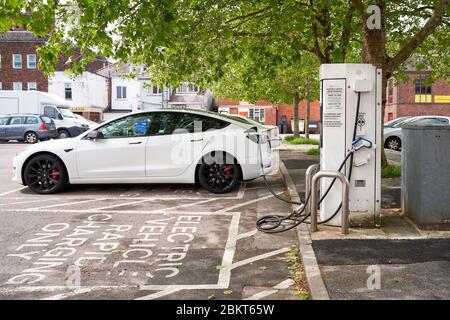 Voiture électrique Tesla modèle 3 branchée à la station de charge Banque D'Images