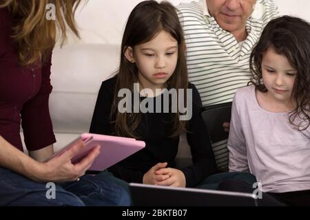 Famille enseignant les enfants à la maison sur les appareils électroniques Banque D'Images