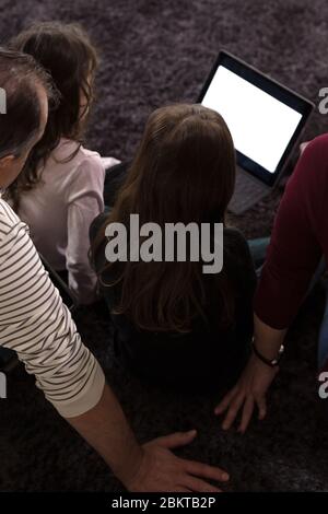 Famille enseignant les enfants à la maison sur les appareils électroniques Banque D'Images