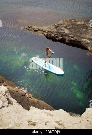 Femme pagayant à bord de SUP dans une mer. Banque D'Images