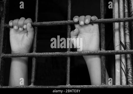 Mains d'un jeune enfant qui embrase les barreaux de prison. Enfant en prison. Triste petit garçon forcé de rester à la maison comme le coronavirus pandémique, covid19. Banque D'Images