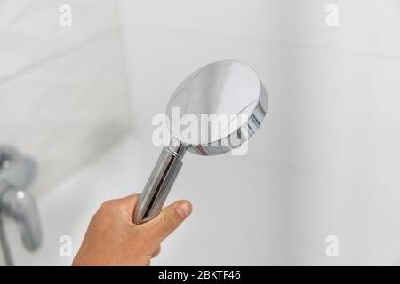 Pomme de douche dans la main dans la douche dans une salle de bains moderne. Banque D'Images