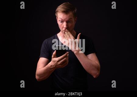Portrait de jeune homme séduisant en utilisant le téléphone et à choqué Banque D'Images