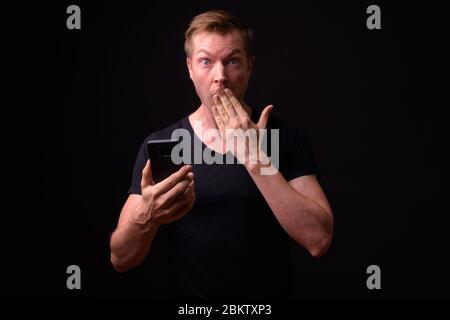 Portrait de jeune homme séduisant en utilisant le téléphone et à choqué Banque D'Images